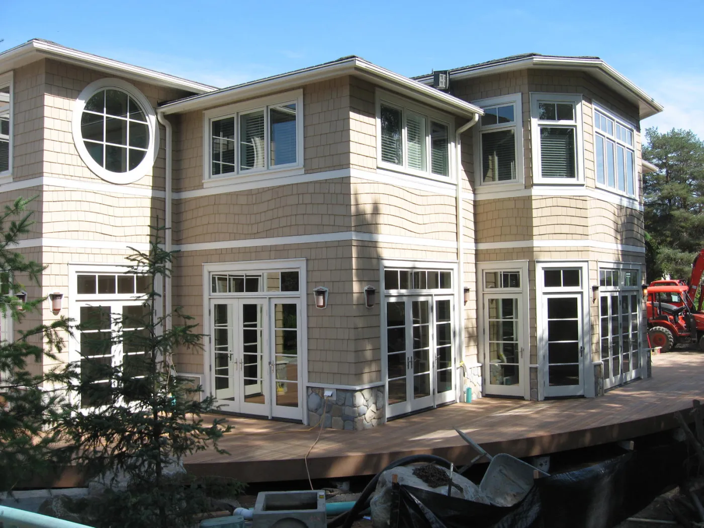 Bellevue custom home: a three-storey shingled house with a round window and a tower bay, among evergreens